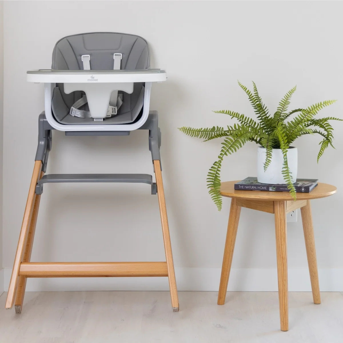 Front view of the grey MOOSE Frankie Foldable High Chair with feeding tray, safety harness and wooden legs.