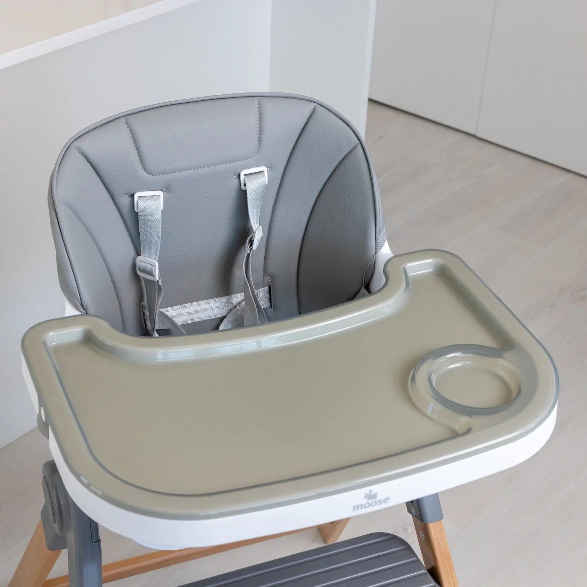 MOOSE Frankie high chair showing the grey padded backrest, safety harness and feeding tray with cup holder.