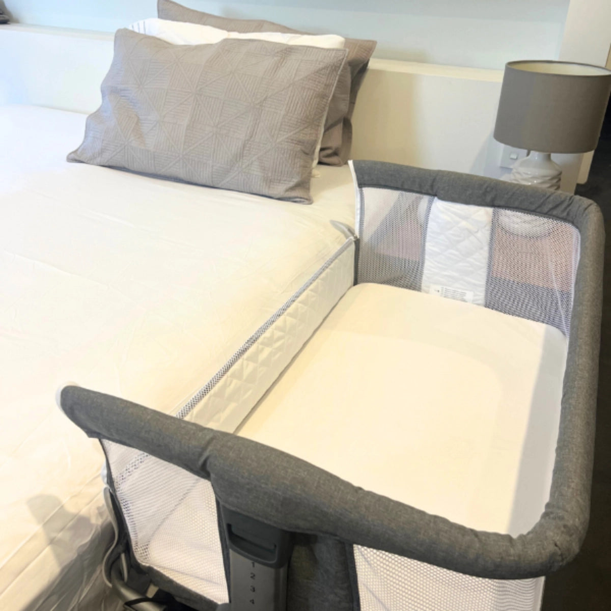 Eden Co-Sleeper Crib with the bedside panel lowered, showing the mattress beside an adult bed.