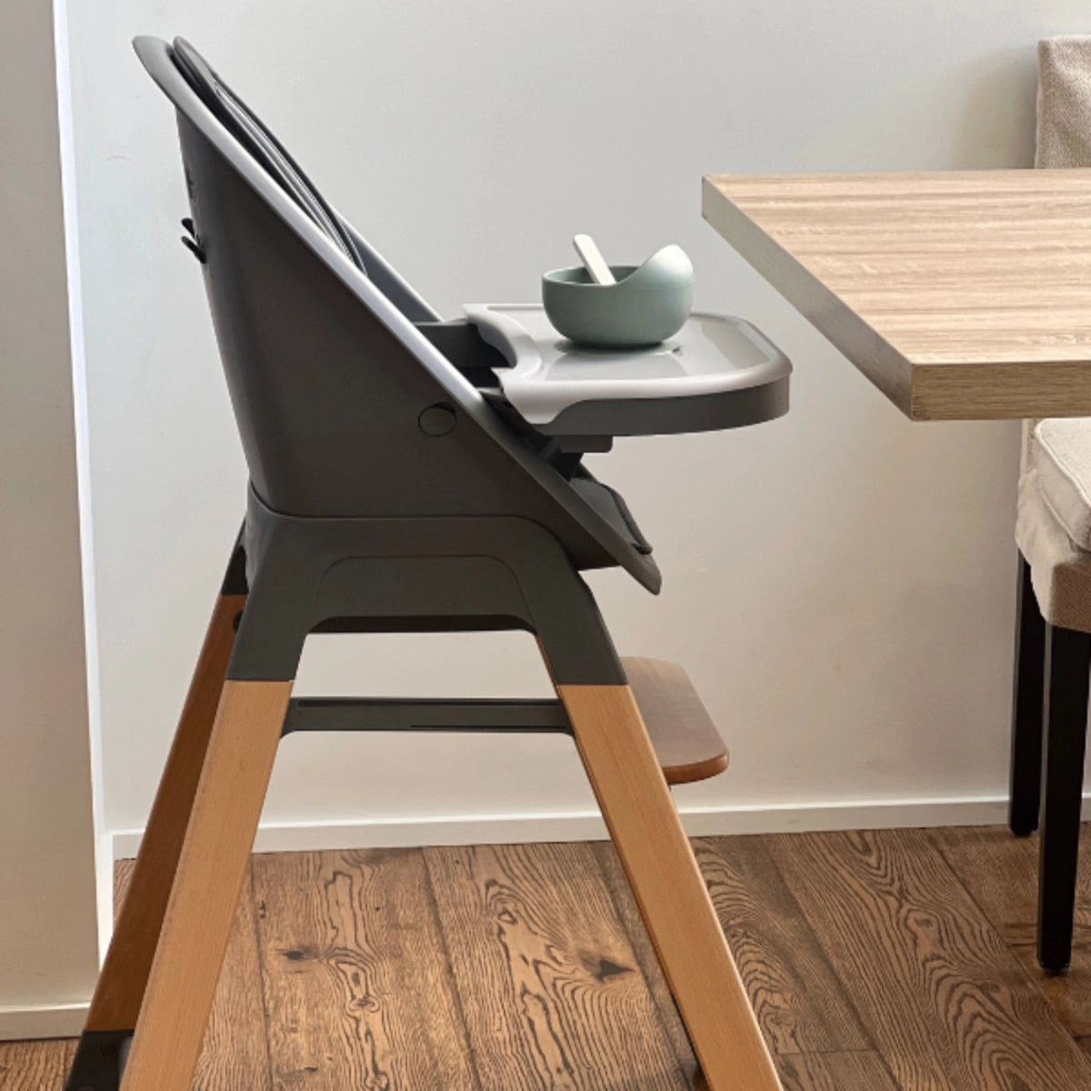 Side view of the MOOSE Harper High Chair showing natural wooden legs and adjustable footrest.
