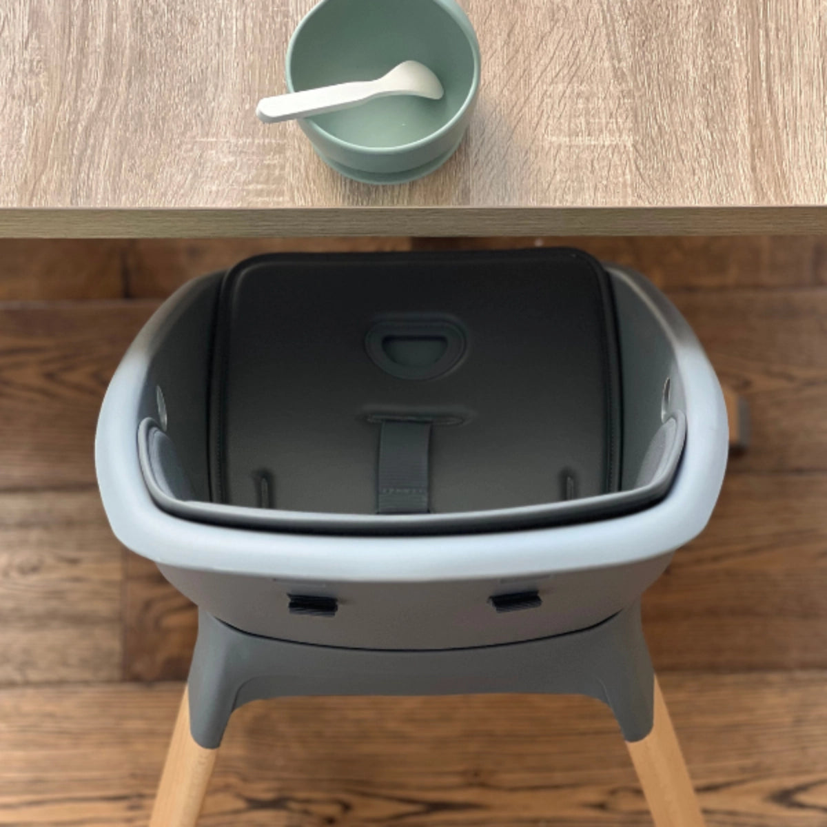 Front view of the MOOSE Harper High Chair positioned at a dining table with the tray removed.
